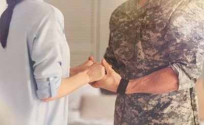 A uniformed soldier holds hands with his wife