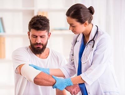 A doctor places a bandage wrap on a patient's upper arm