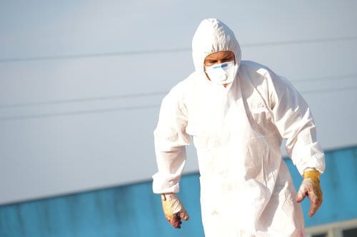 Man in hazmat suit removing asbestos from shipyard