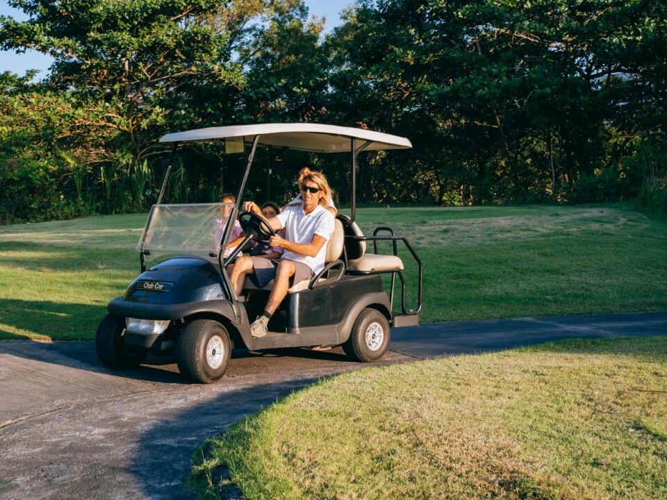 Men driving golf cart on trail.
