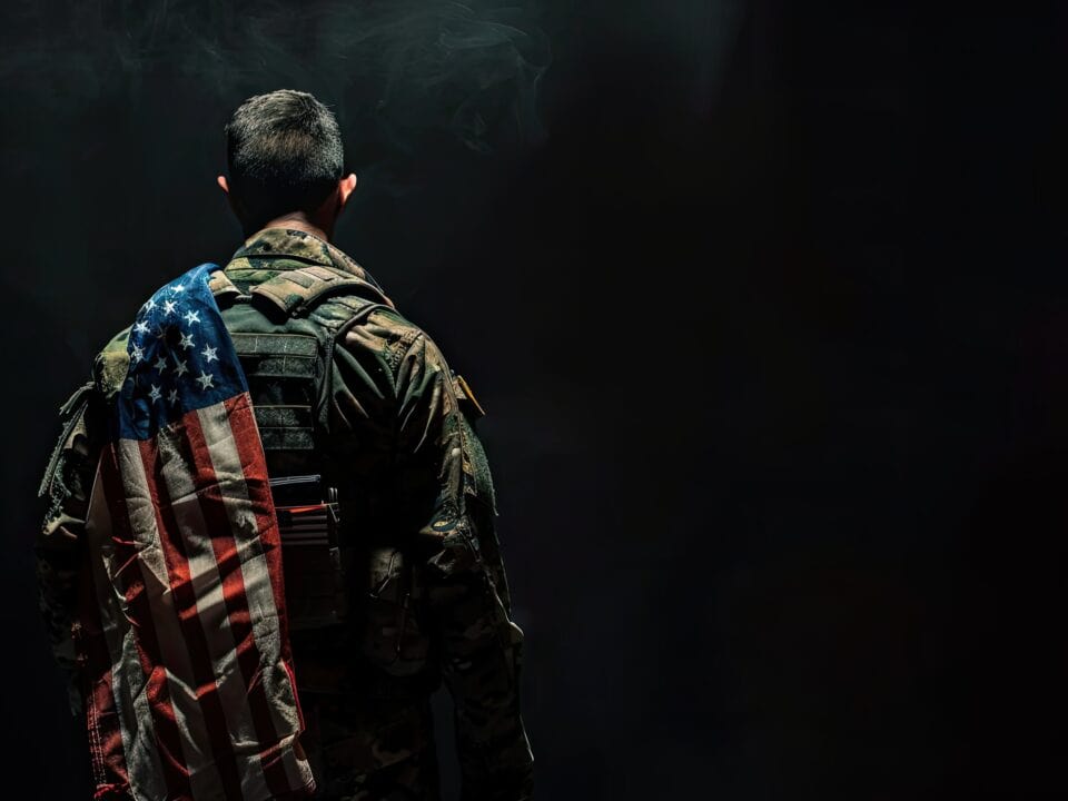 A soldier proudly carries an American flag on his back